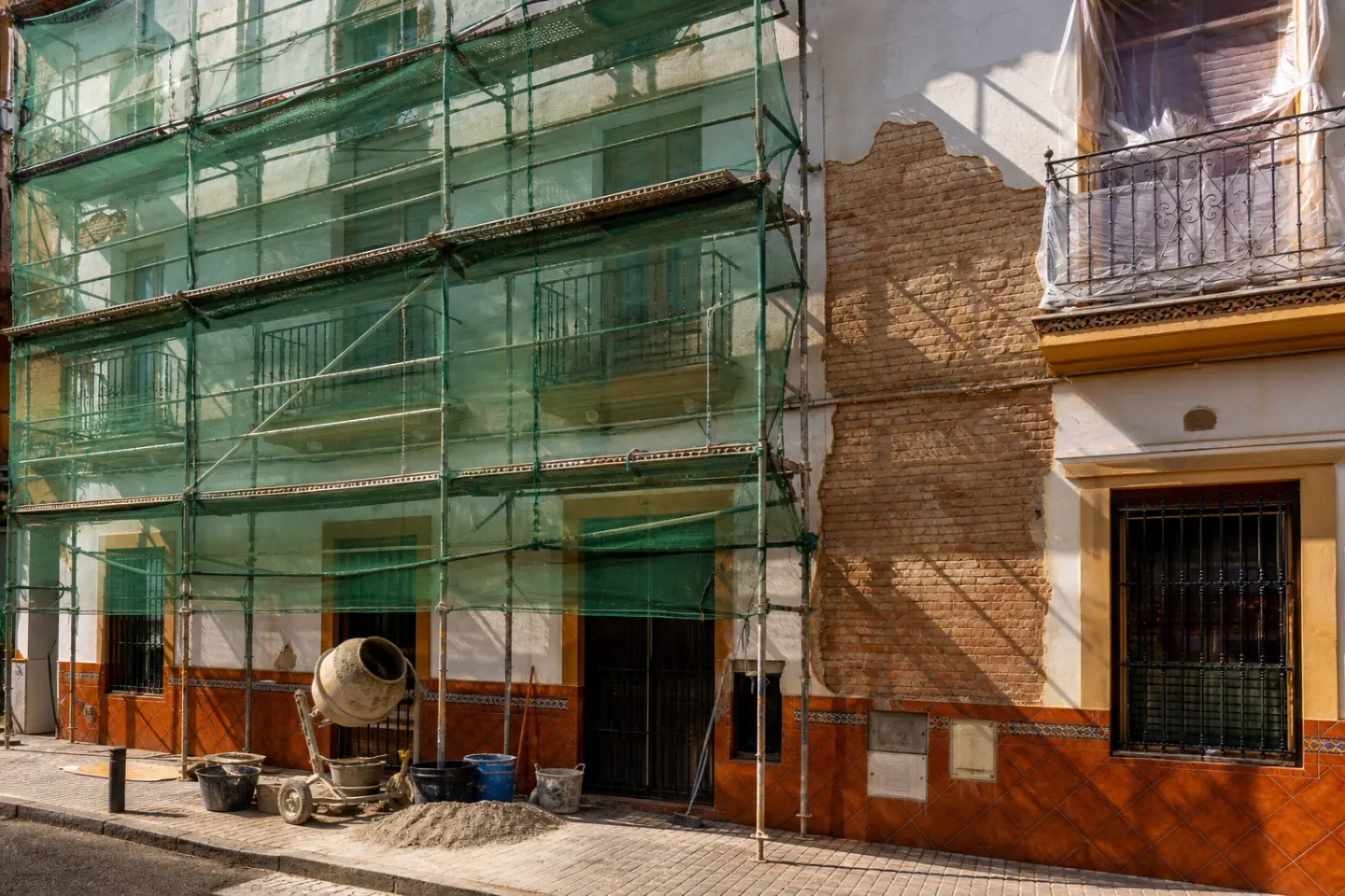 Andamio montado sobre la fachada de un edificio de ladrillo y cal en rehabilitación
