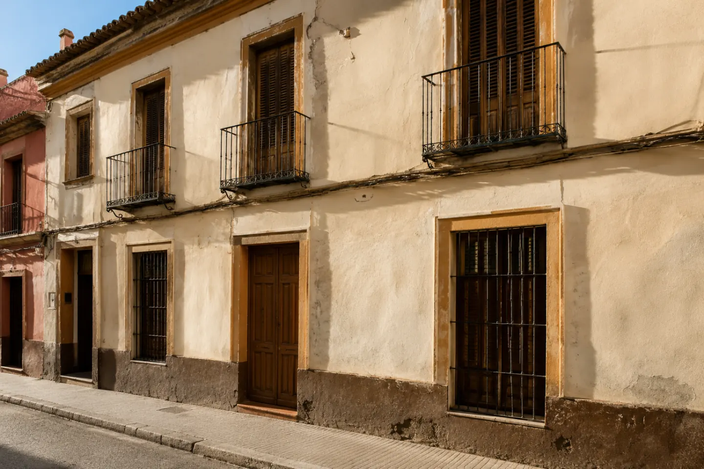 Fachada histórica anónima con revoco de cal, zócalo y carpintería de madera