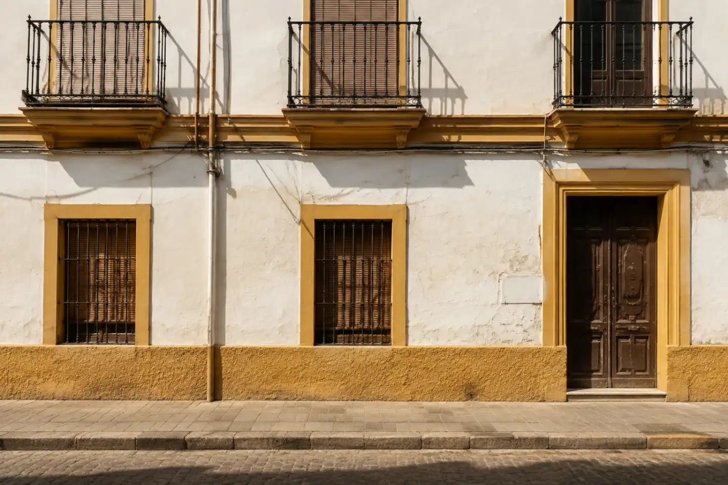 Fachada histórica anónima de Sevilla con huecos, zócalo y textura tradicional