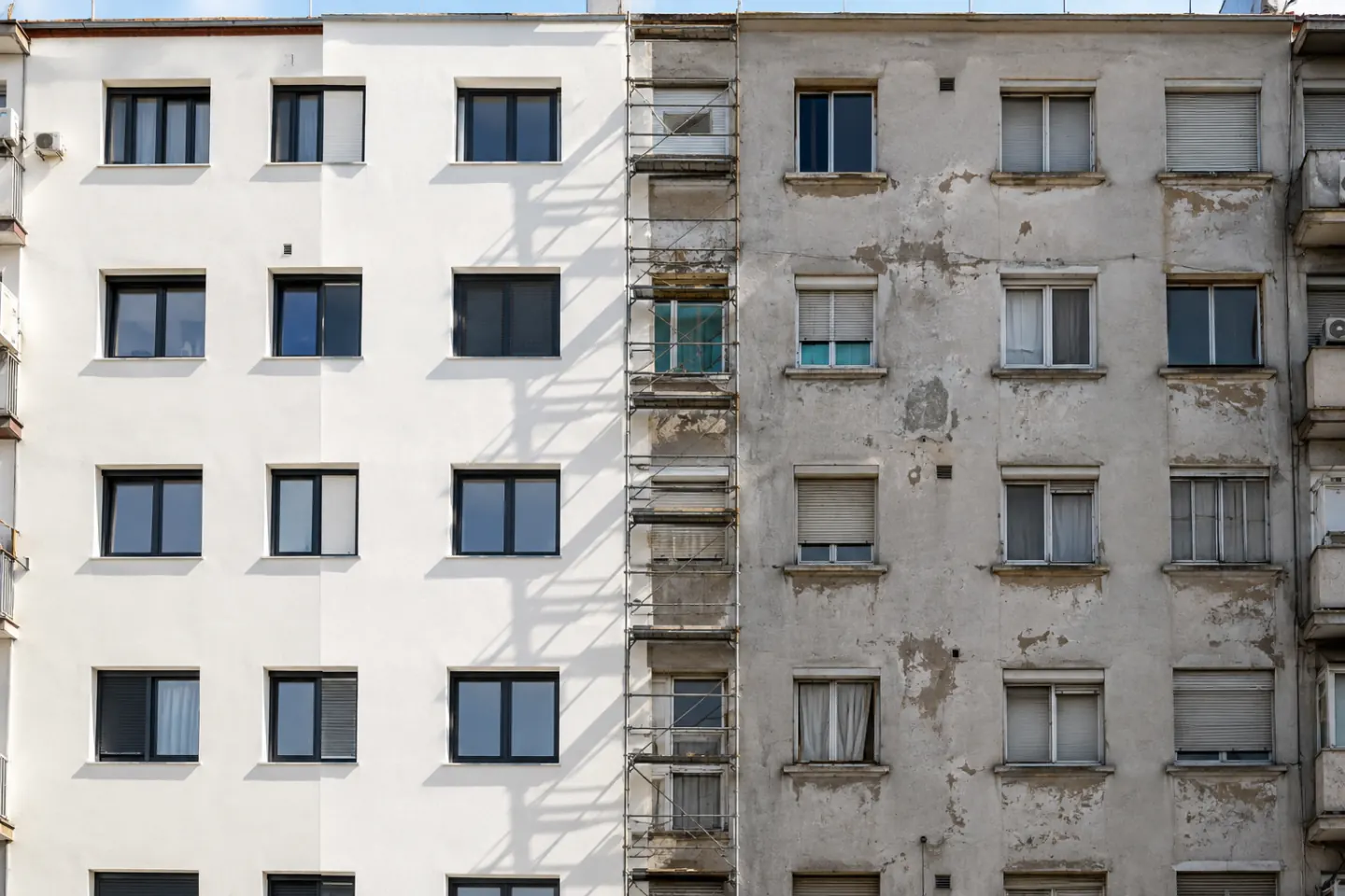 Fachada de un edificio de viviendas con una mitad ya rehabilitada y la otra sin tocar