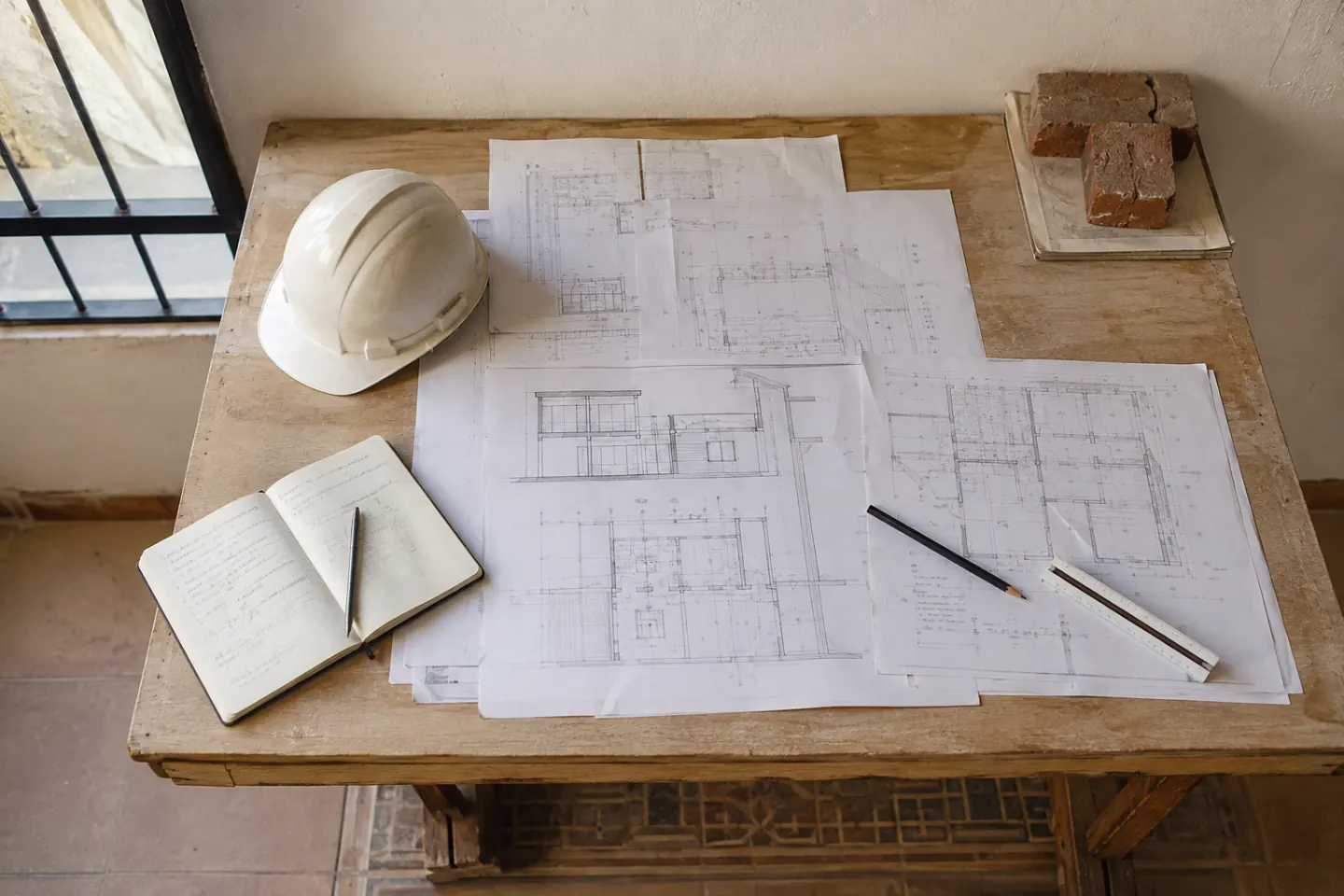 Planos de ejecución, casco y cuaderno técnico sobre una mesa de obra