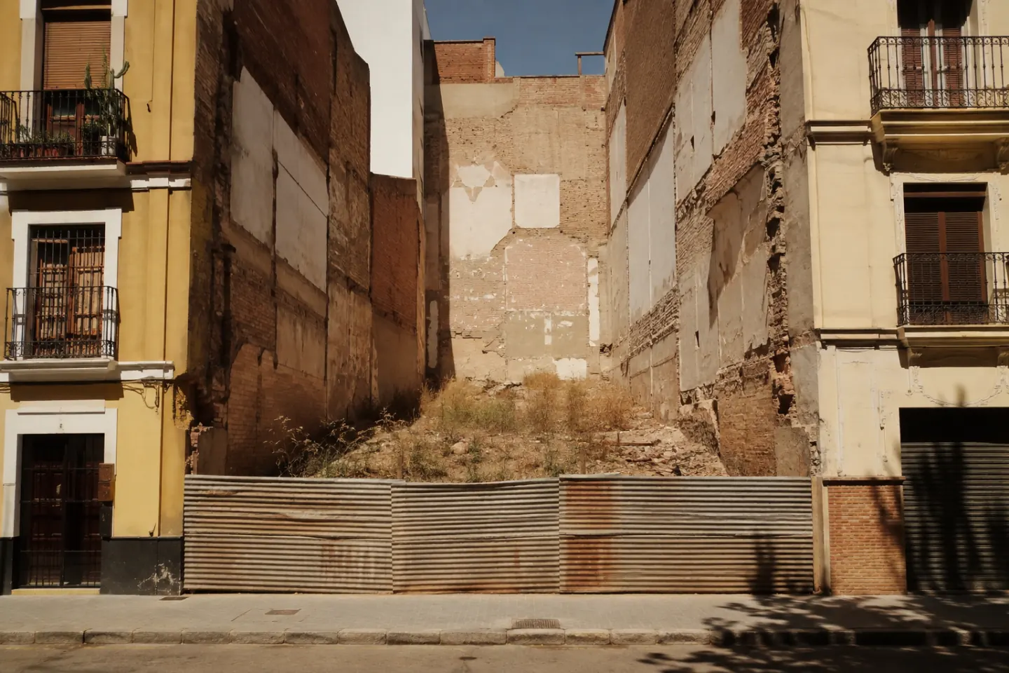 Solar vacío entre dos medianeras en una manzana consolidada, visto desde la calle